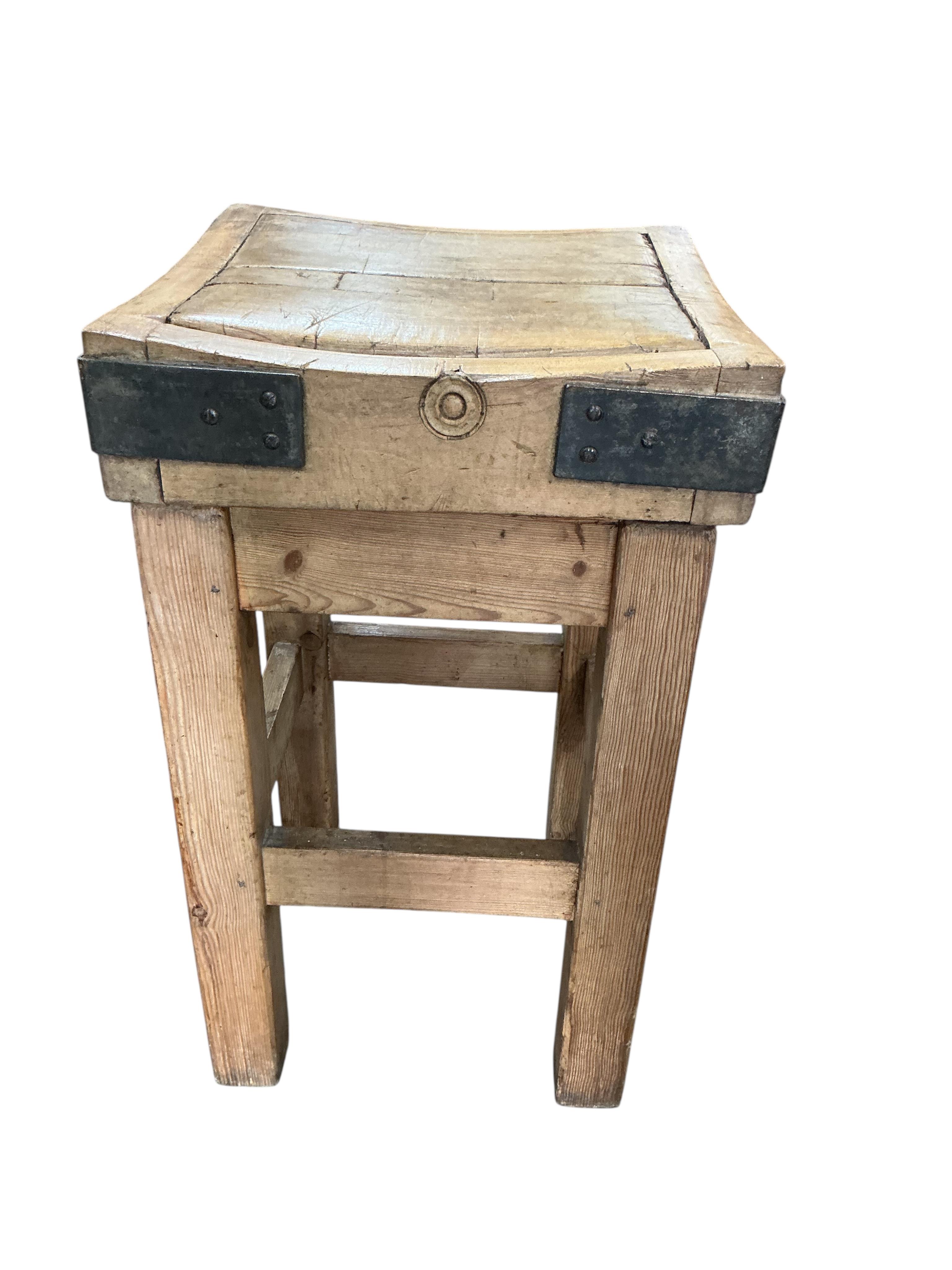 A small iron bound butcher’s block on stand bears metal plaque 